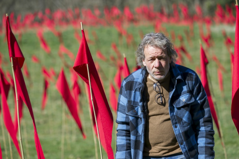 Jean-Paul de Vries devant une partie des 16.800 drapeaux rouges disposés dans la vallée de la Robinette à Romagne-sur-Montfaucon, dans la Meuse, le 20 mars 2025