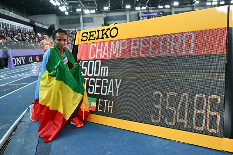 L'Éthiopienne Gudaf Tsegay pose a côté du chrono de son record des Championnats du monde en salle du 1.500 m après son titre aux Mondiaux de Nankin, en Chine, le 23 mars 2025