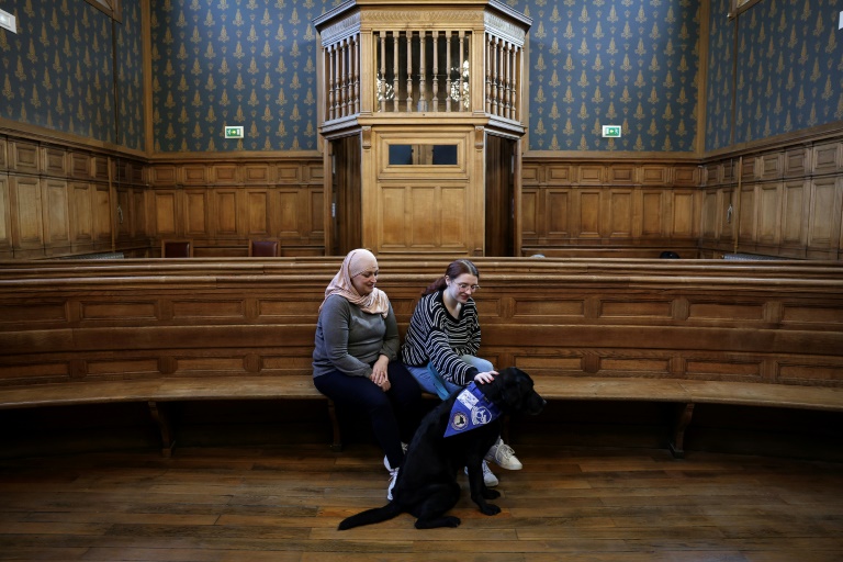 Mathilde (d), sa mère Natalia (g) et le labrador Lol, premier chien d'assistance judiciaire, au tribunal de Cahors, le 14 février 2025 dans le Lot